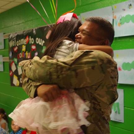 Father, daughter reunite at school Army Sergeant First Class Roland Tajalle and his daughter RaiþÄôAna, 5, embrace each other in the main hall of Walnut Ridge Primary School.