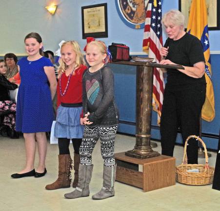 From the left, three nine-year-old girls from Newton helped with the ceremonies at the Sussex Elks: Mackenzie Genung, Danielle Penny, and McKenzie Emanuel. The girl&#xfe;&#xc4;&#xf4;s service group is called, &quot;Everyone&#xfe;&#xc4;&#xf4;s Helping Hand&quot; and veterans are a group they wish to help. At the podium is Elks member and emcee Carol Lee Spages.