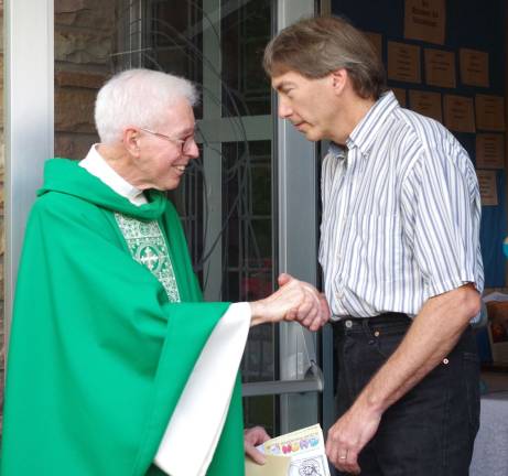 Celebration in honor of Father Bob’s retirement John Cawley of Highland Lakes, who assisted Father Bob for many years during the church's annual biker blessing, shakes hands with Father Bob after the retirement service.