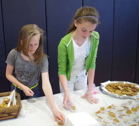 Hannah Van Blarcom, 13, and Amelia Dawes, 13, prepare tasy offering form the Holland American Bakery.