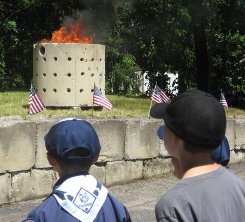 Boy Scouts watch as flags are consumed in flames.
