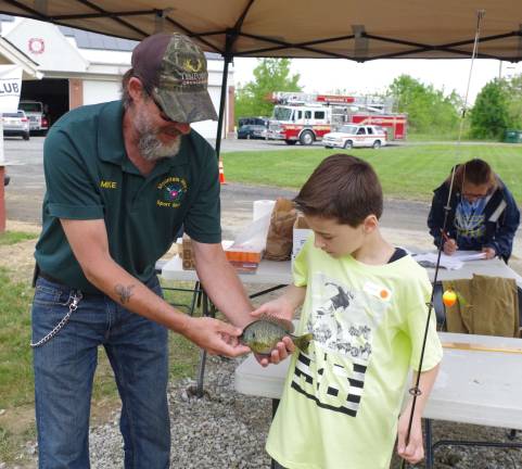 Third grade student Adem Istrefi, 9, and his 7-3/4-inch sunfish are shown with Mike Bush of Mountain Mike&#xfe;&#xc4;&#xf4;s Sport Shop. He was one of seven children in the Grades 3-6 division who went home with a trophy.
