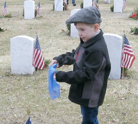 Four-year-old Joseph of Wantage scatters flag ashes on his grandpa, Kenneth Fuchs Sr’s grave.