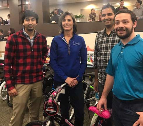 Andy Moulakis, Phani Povanki, Mindy Ooston and Tim Guppla proudly stand with the bike they assembled representing the Actuarial Department.