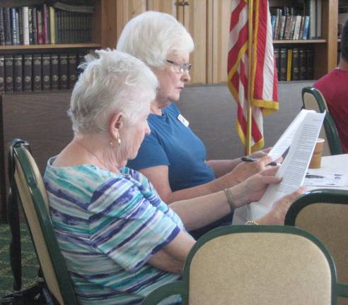 Two ladies of the audience intently follow the reading of the Declaration of Independence.