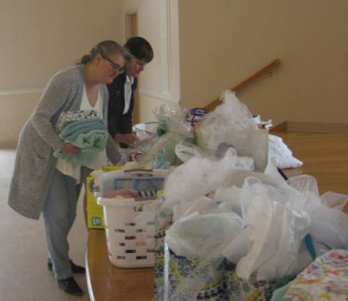President Janet Tussey (background) and Linda Stengel organize donated items at the Mother&#xfe;&#xc4;&#xf4;s Day tea held at St. Francis de Sales Church.