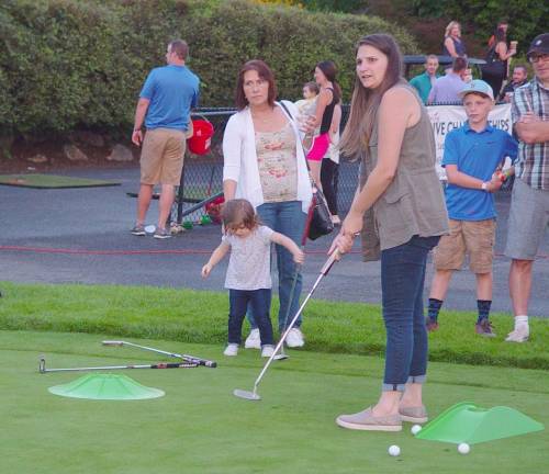 Mom gives it her best in the Putting Contest as family looks on