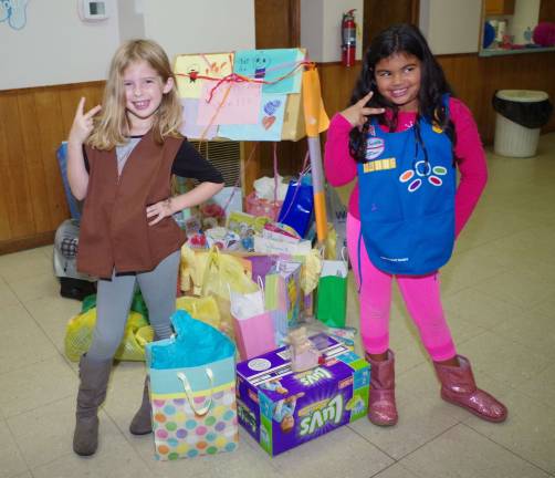 Girl Scouts Stephanie Smith, 8, and Faith Kliemisch, 6, are shown standing with the items they donated to Birth Haven at their feet. Many additional items donated by the other scouts are behind them.