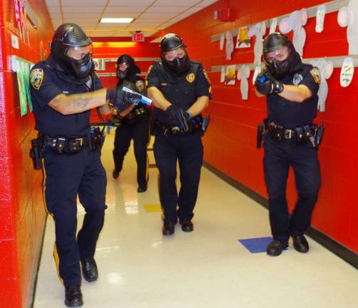 With weapons drawn, four Vernon Township police officers walk down the main hall at Walnut Ridge Primary School searching for three active shooters in the school and two hostages being held in a classroom.