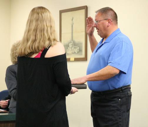 Robert Holowach is sworn in for another three-year term as a Councilmember by Mayor Katherine Little, as his daughter Emily holds the bible.