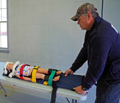 Squad member Michael Puskas demonstrates a special piece of equipment meant to immobilize and transport an injured child.