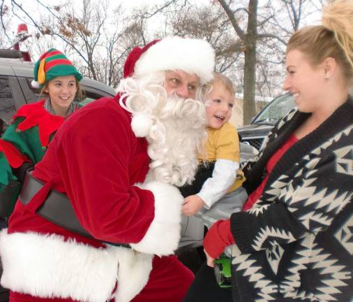 Santa Claus rides through Lake Neepaulin Travis Vaughn of Summit Drive displays a smile of contentment as Santa embraces him.