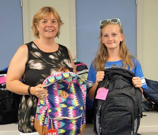 From left, Ginnie's House Volunteer and Event Coordinator Maryane Mitchell and Hannah stand before the completed backpacks.