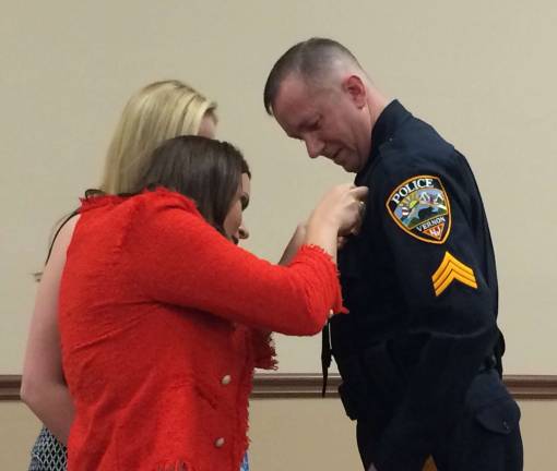 Members of Sgt. Scott Waleck's family pin his new badge to his uniform following his promotion from Corporal to Sergeant in the Vernon Police Department.