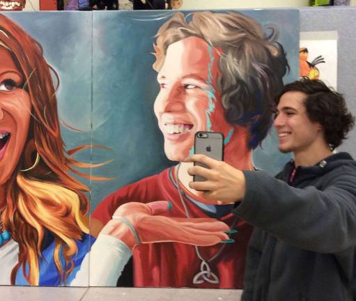 VTHS art teacher creates student art gallery Jeremy Bennett takes a selfie with his image on the huge three-panel painting Miller completed.