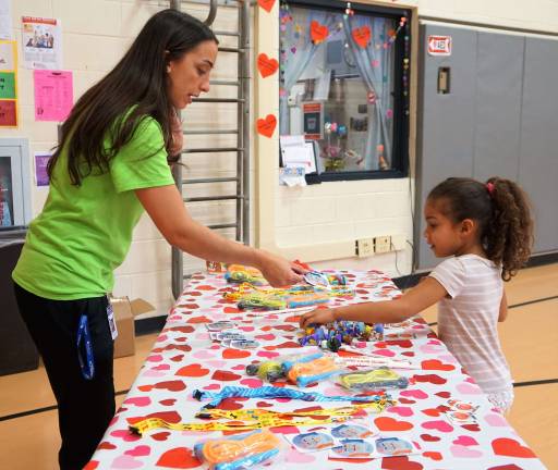 Teacher Michele Gonnelli gives a sticker to a student picking a raffle prize.