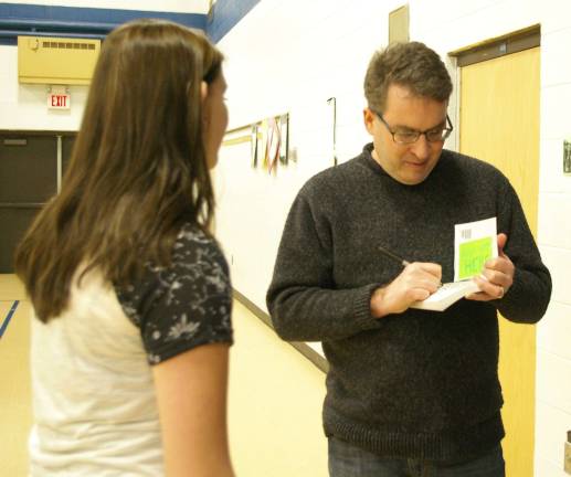 Photos by Chris Wyman Author Jordan Sonnenblick is shown autographing one of his novels for a student.