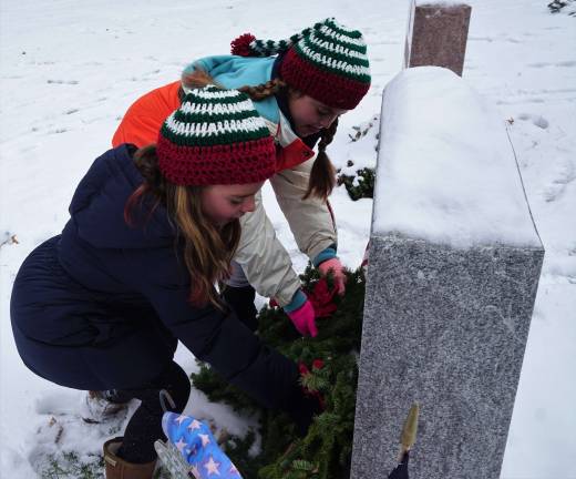 Young volunteers place wreaths in honor of one who served.