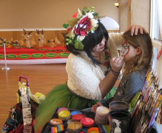 Barry Lakes Holiday Party Dixie Pop the Clown works on face painting for Layla Blanchard.