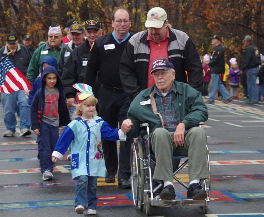 World War II veteran John Beatty and his great-granddaughter Emily Leve, 5, are shown leading the parade of veterans at Walnut Ridge Primary School.