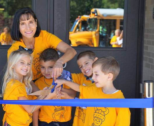 Principal Rosemary Gebhardt cuts the ribbon with students.