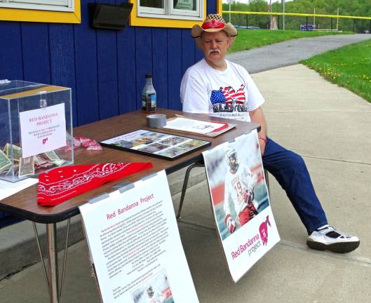 Phil Tintle is shown collecting donations for the Red Bandanna Project during the Vernon lacrosse team&#xfe;&#xc4;&#xf4;s victory over High Point Regional High School. Assisting him at the table was Megan Graham, a Vernon High School senior and recipient of the Welles Crowther Award.