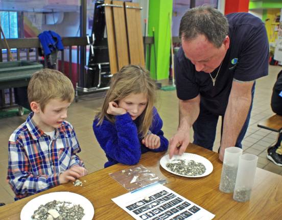 Paleontologist John Miller helps Bella Brooks, 9, to better understand the materials that she is searching through.