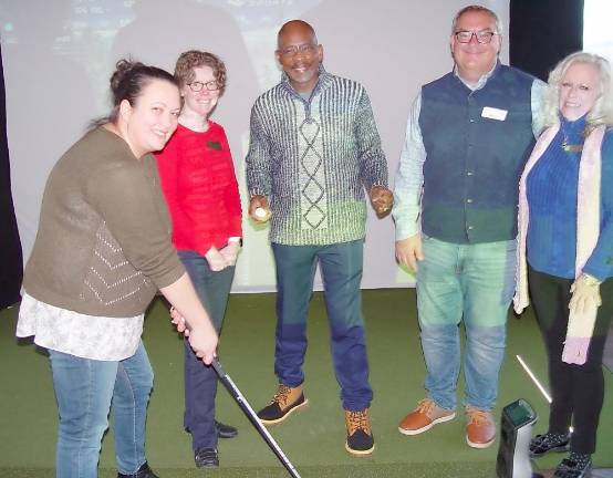 Hef’s Hut opens with golf simulator, pool table, and heated patio — and attracts locals Vernon Mayor Howard Burrell (center) provides golf tips to Jennifer Lubliner, Vernon’s Economic Development Advisory Committee chair. They are pictured with Debbie Coulson, recording secretary for the Vernon Chamber of Commerce; David Killin, Great Gorge Golf Club general manager; and Elizabeth Cassidy, Warwick Chamber of Commerce President (Photo by Dr. John T. Whiting)