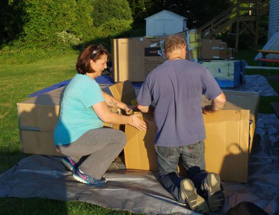 At center Davida Schnebelen, left, and Graham Hall reinforce a makeshift corrugated box shelter.