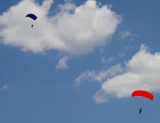 One tandem (left) and one solo skydivers descend to the airport field below.