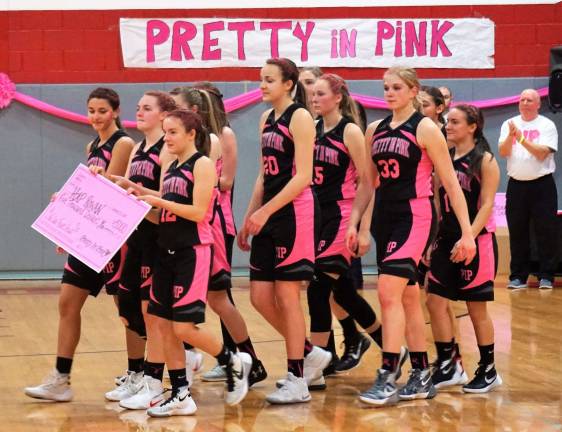 The High Point Girls' Varsity team carries a Pretty in Pink check to be presented.
