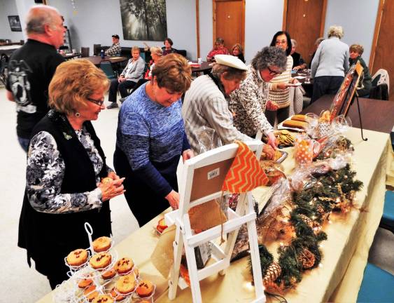 Volunteers and members at the Vernon Senior Center reach for baked goodies donated by student volunteers from Vernon Township High School and check out the raffle prizes, donated by a local family.