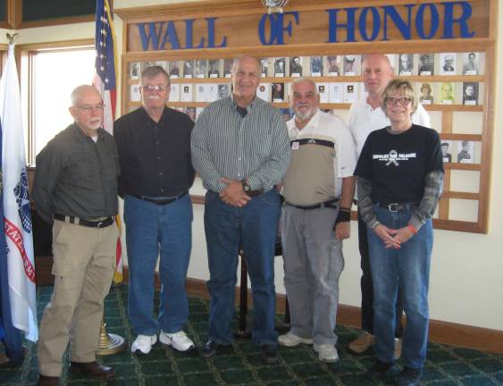 Four vets and Nancy Wolfe of Supplies for Soldiers pose at the Wall of Honor, a permanent veterans&#x2019; tribute.