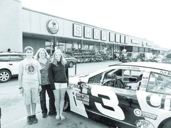 Jeffrey Schnebelen, Live Hopkin, and Julia Kotkin from Vernon United Methodist Church pose next to the Cheerios race car to raise awareness and funds for the Church&#x2019;s food pantry.