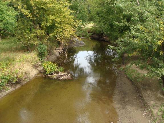 A view from the bridge shows the Wallkill River serenely flowing