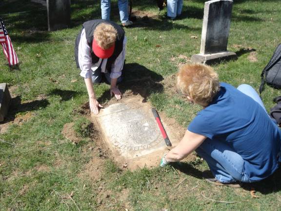 DAR cemetery dig DAR members Nancy Malone, left, and Lisa Permunian carefully work to uncover a grave marker that has been buried over time. Photos by Scott Baker