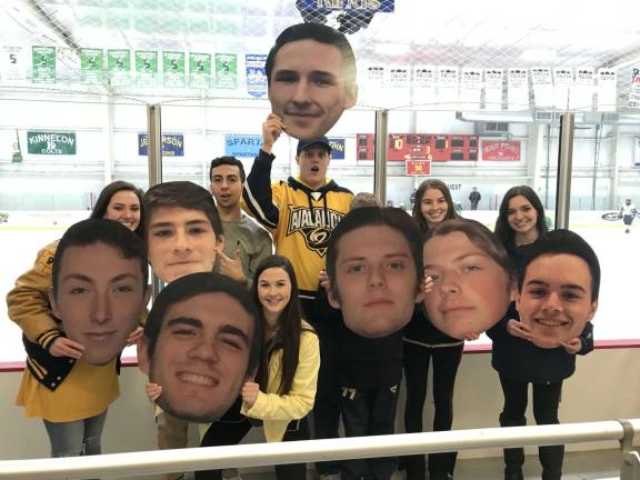 Fans hold up cutouts of the Vernon ice hockey's teams seniors.