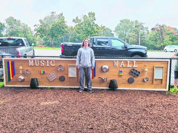 Matthew Okken stands by the Music Sensory Wall that he built at Walnut Ridge Elementary School.