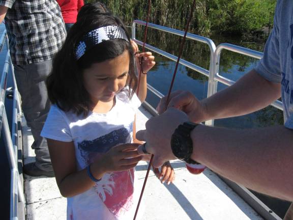 Nature kids go fishing at the refuge A squirmy worm, no problem for this fisher girl.