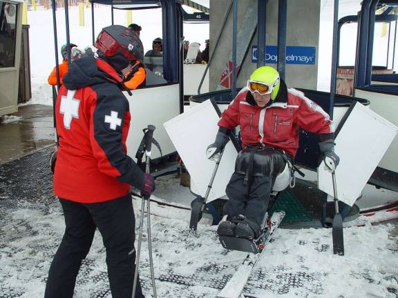 The PSIA adaptive instructor demonstrates how to enter the Cabriolet lift by backing into the cab with Susanne Ebling observing.