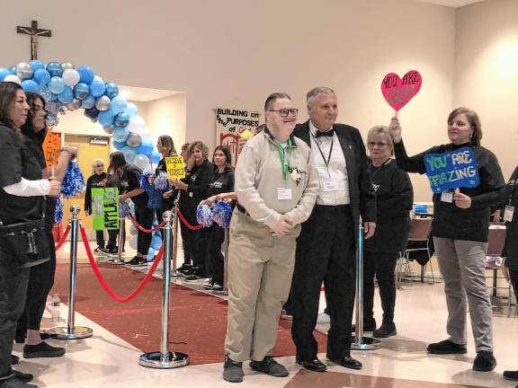 Giving others a Night to Shine <b>Volunteers welcome a guest and his buddy walking the red carpet into the prom.</b>