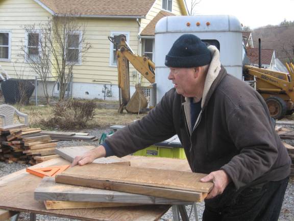 A volunteer carefully measures construction wood.