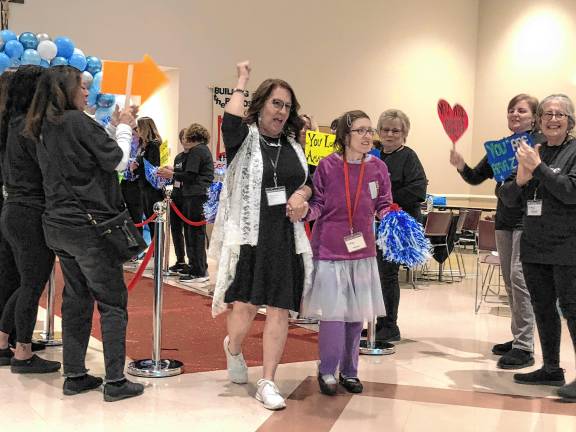 Giving others a Night to Shine <b>Volunteers welcome a guest and her buddy walking the red carpet into the prom.</b>