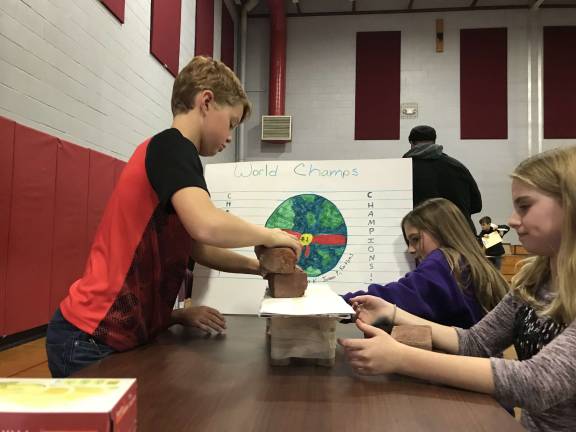 Area students build bridges Team World Champions test their bridge with a brick.