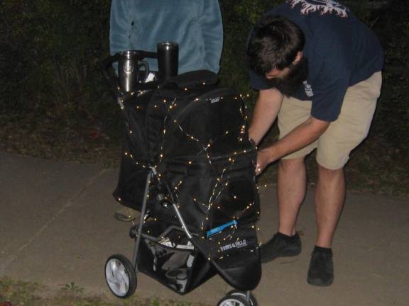 Some participants shined it up with headlamps, lighted crowns and even lit strollers. Lights are being checked on this stroller, on board was a cat.