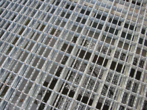 The surface of the bridge is a metal grid with the water visible below.