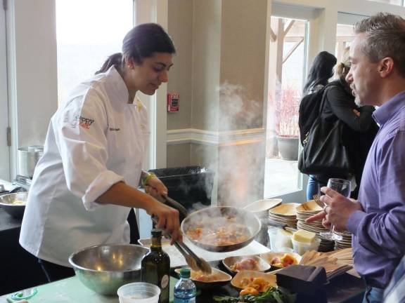 Chef Silvia Barban fills a bowl with food while talking to a guest. Barban is the executive chef at Aita, a restaurant in Brooklyn, New York.