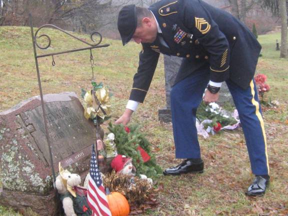 Sergeant First Class Fernando Cova-Gomez places a wreath on a fellow veteran&#x2019;s grave.