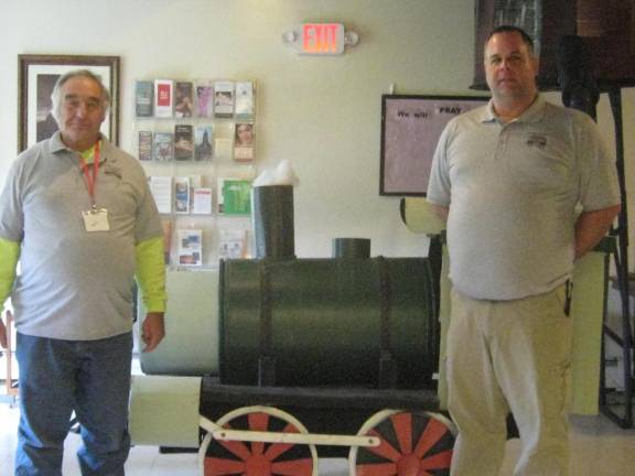 Sussex County Railroad Club Treasurer Bob Winter, left, and club President Stephen Zydon pose near a constructed train engine and water tower in the church’s lobby.