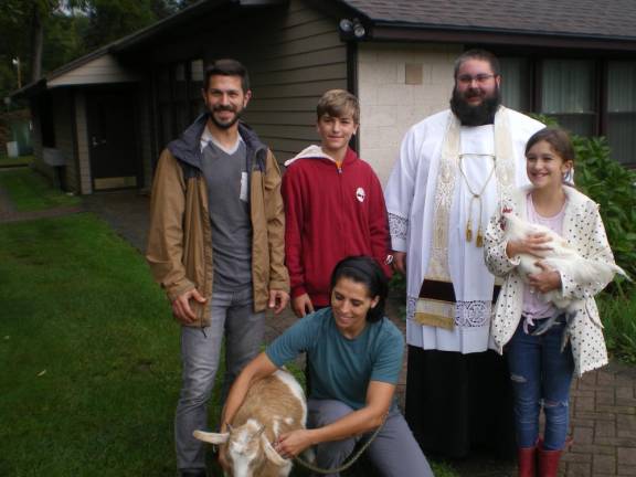 The Mancini family, Father Chris Barkhausen, Blue the rooster and Lucy the goat pose after their blessing.